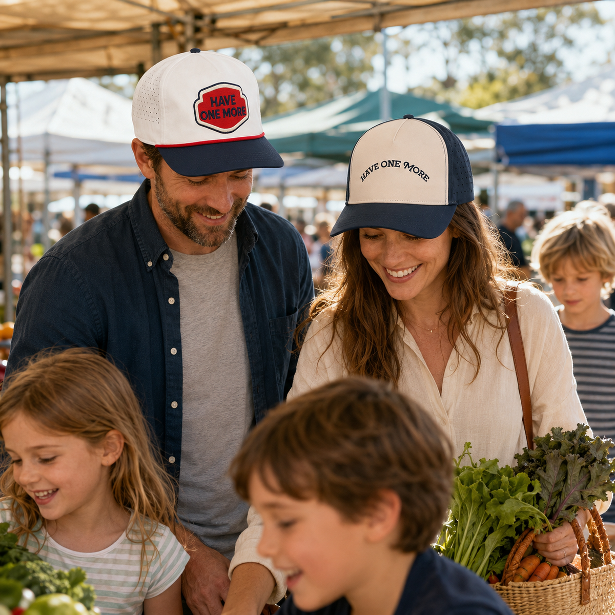 Parents wearing both Have One More hats with their children at a farmers market
