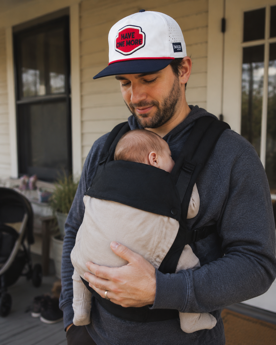 Father wearing the Have One More BOCO Lowdown Trucker Hat while carrying a newborn